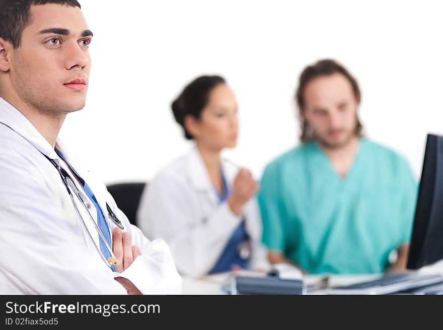 Young doctor thinking deeply, collegues discussing behind with computer in hospital