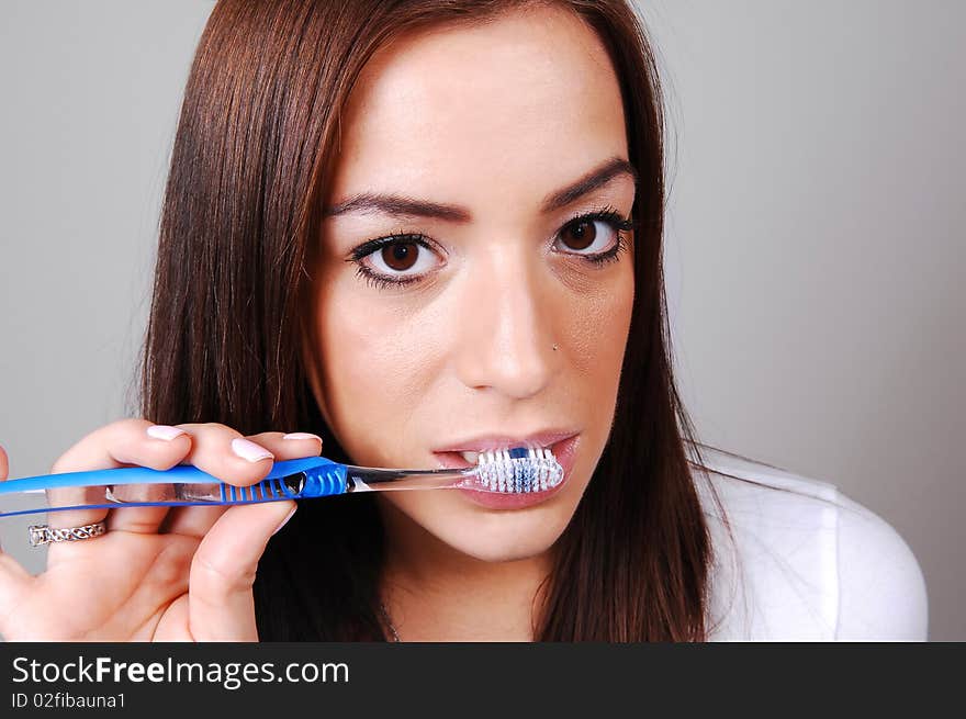 A young brunette woman brushing her teeth wit a toothbrush as a normal
routine after a dinner. A young brunette woman brushing her teeth wit a toothbrush as a normal
routine after a dinner.