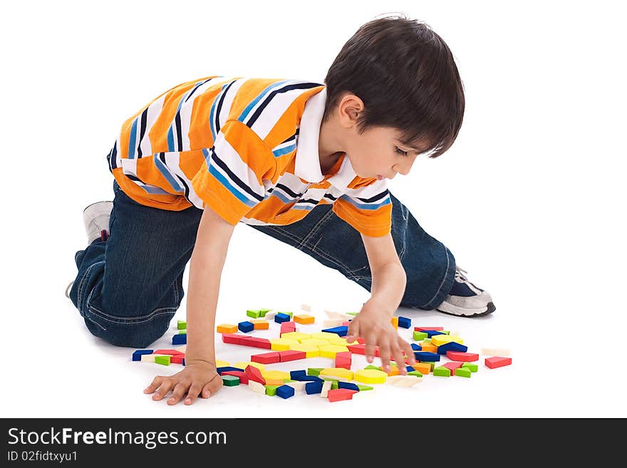 Cute kid in process of joining the blocks over white background