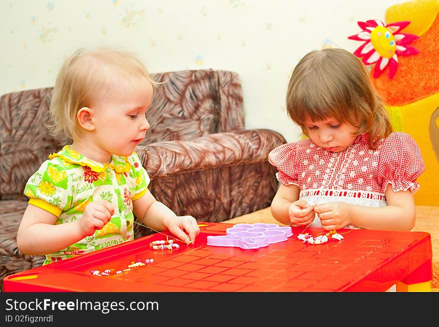 Two girls collect a beads