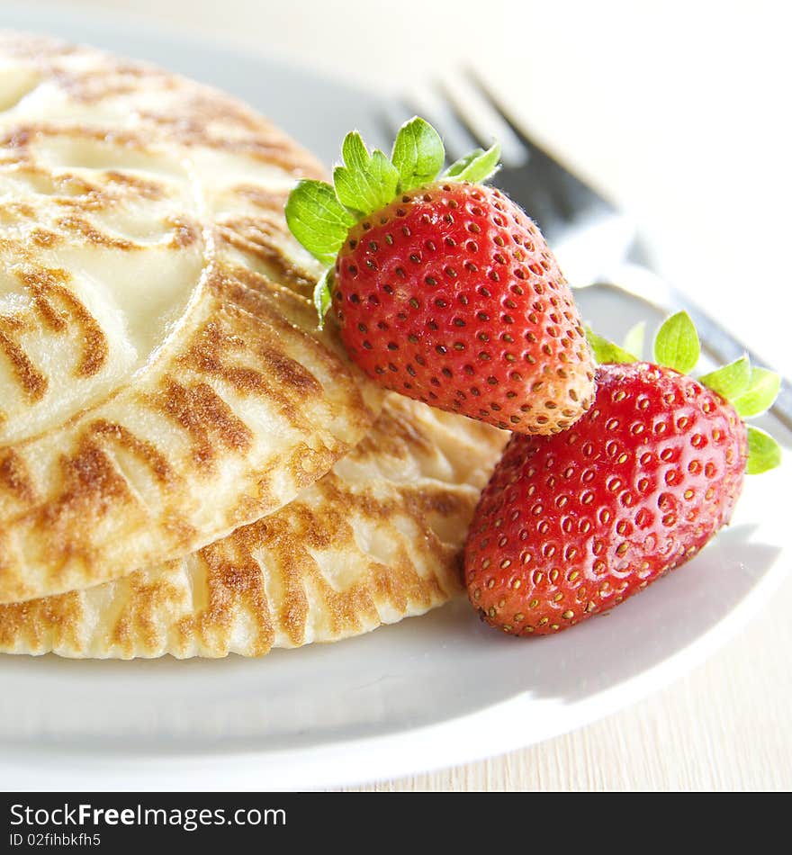 Close up shot of pancakes with strawberries on white plate. Close up shot of pancakes with strawberries on white plate