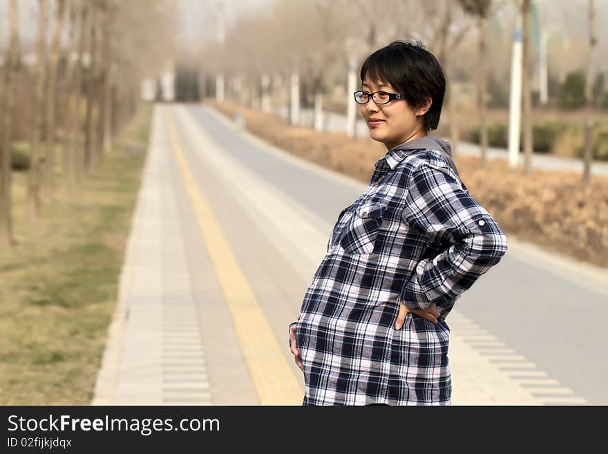 Pregnant woman walks with leisure enjoying warm sunshine in early spring. Pregnant woman walks with leisure enjoying warm sunshine in early spring.