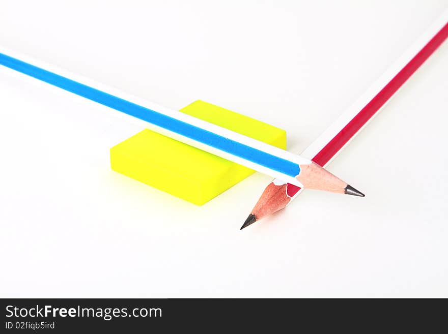 Two colorful pencils and yellow rubber on white crossed