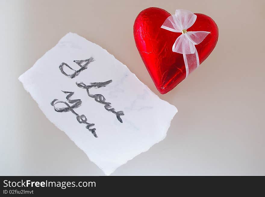 Valentine chocolate heart in red foil with white bow and note