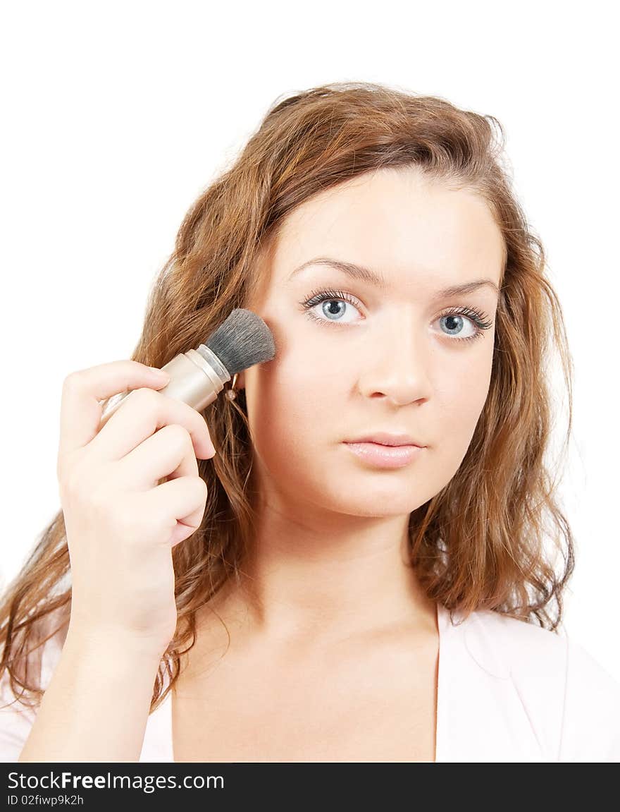 Young woman putting make up on her face. Isolated over white