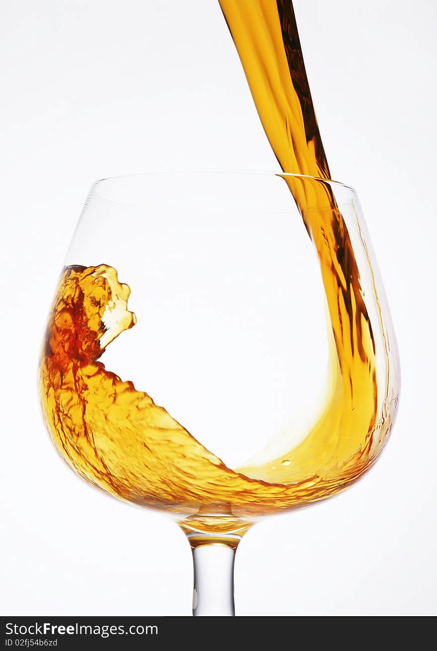 Pour a glass of cognac on a white background