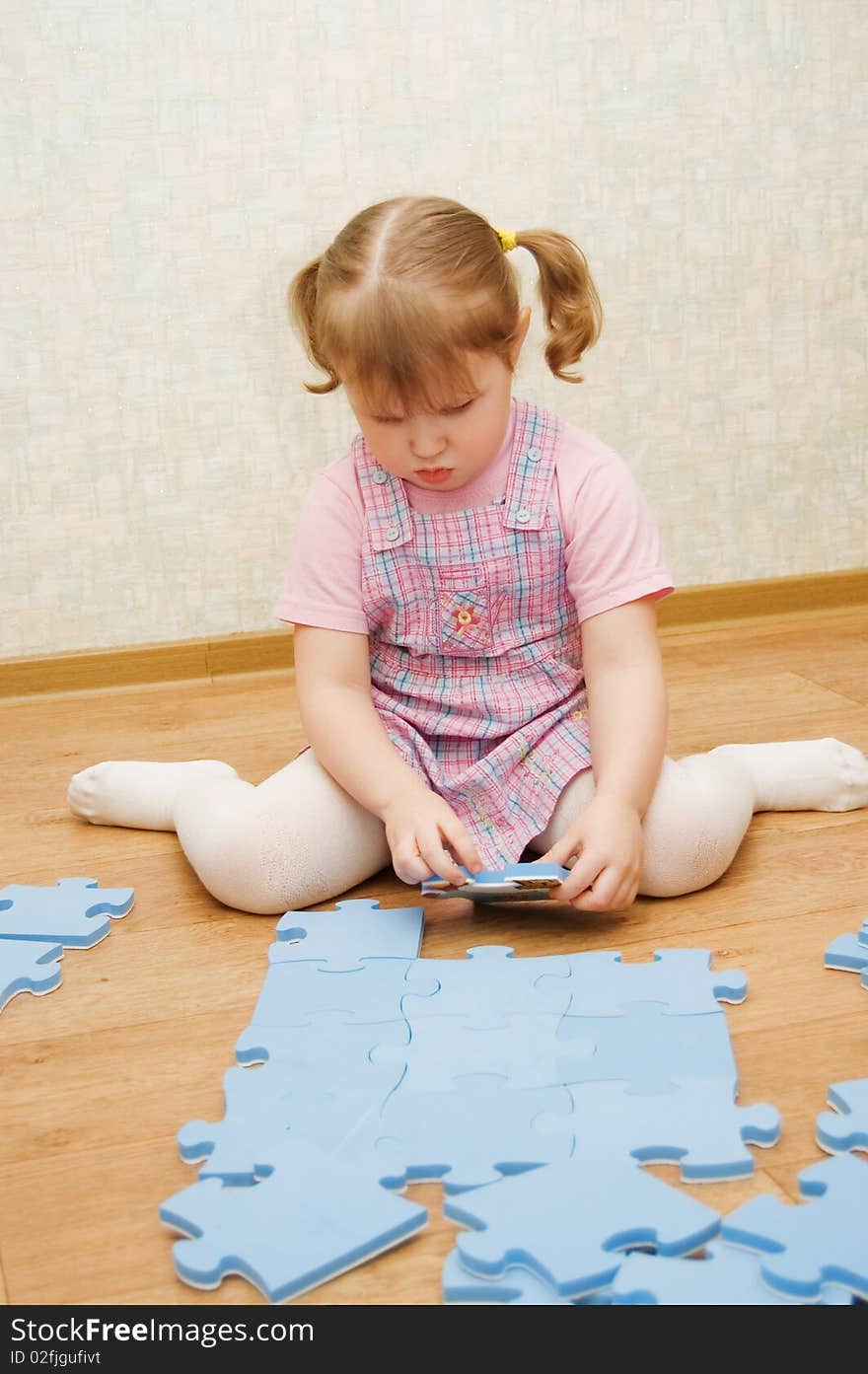 Little girl collects puzzles in a room