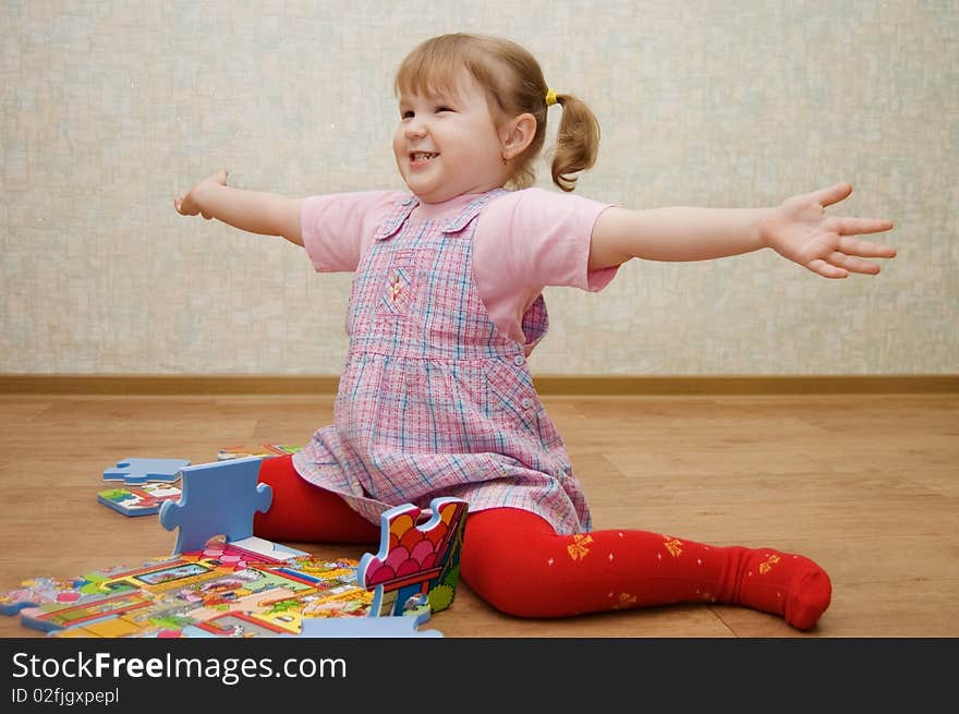 Little girl collects puzzles in a room