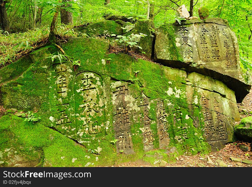 A large rock face covered in ancient text engravings and moss. Taken at a South Korean Temple. A large rock face covered in ancient text engravings and moss. Taken at a South Korean Temple.