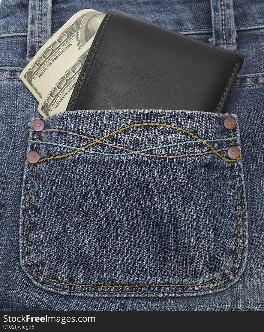 Pocket money. Black leather wallet with dollar bill roll in hip pocket of worn blue jeans close-up.