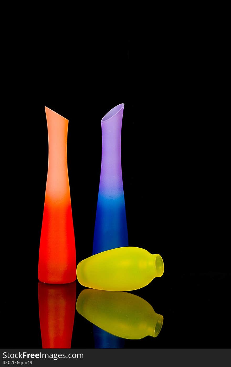 Bright glass vases on black background with reflection