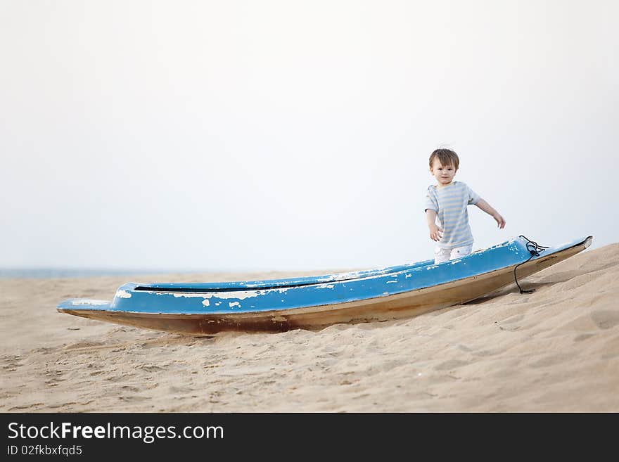 Little boy standing in the boat lying on the beach. Little boy standing in the boat lying on the beach