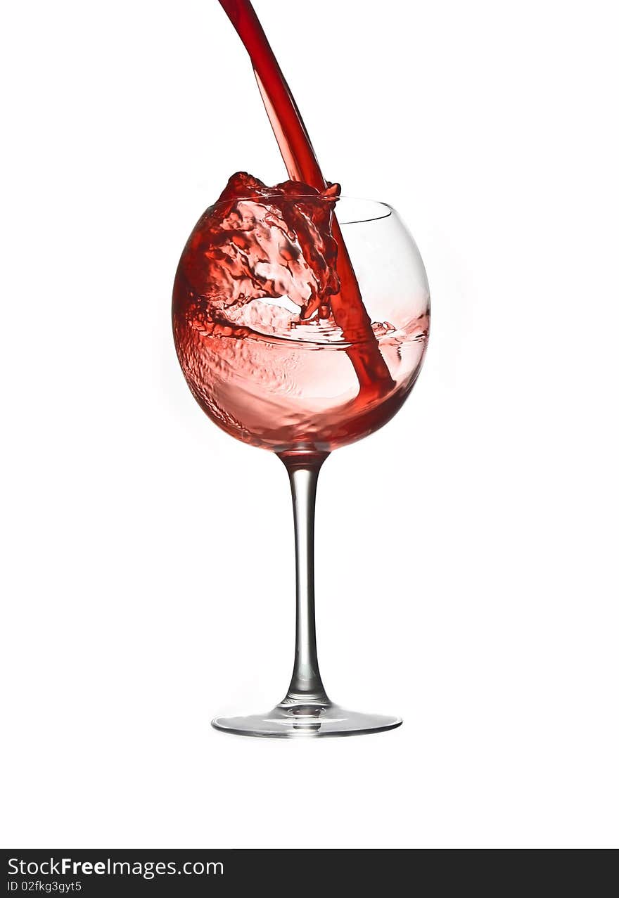 Pouring red wine in large glass isolated white