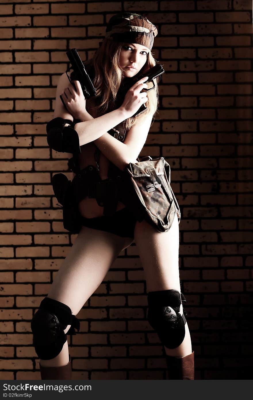 Shot of a sexy woman in military uniform posing against brick background. Shot of a sexy woman in military uniform posing against brick background.