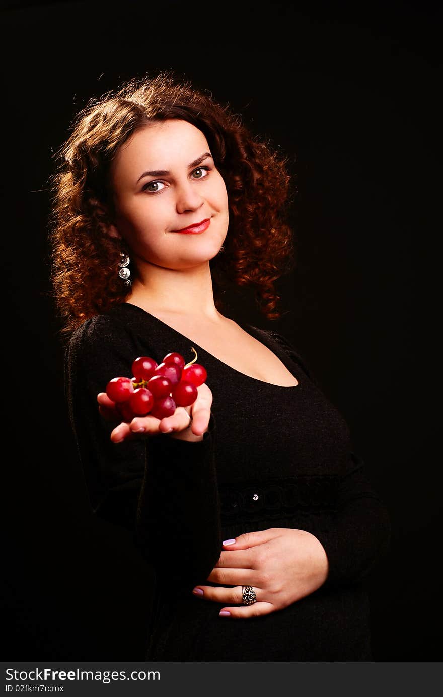 Portrait of a young woman holding grapes on her hand. Studio shot. Portrait of a young woman holding grapes on her hand. Studio shot.