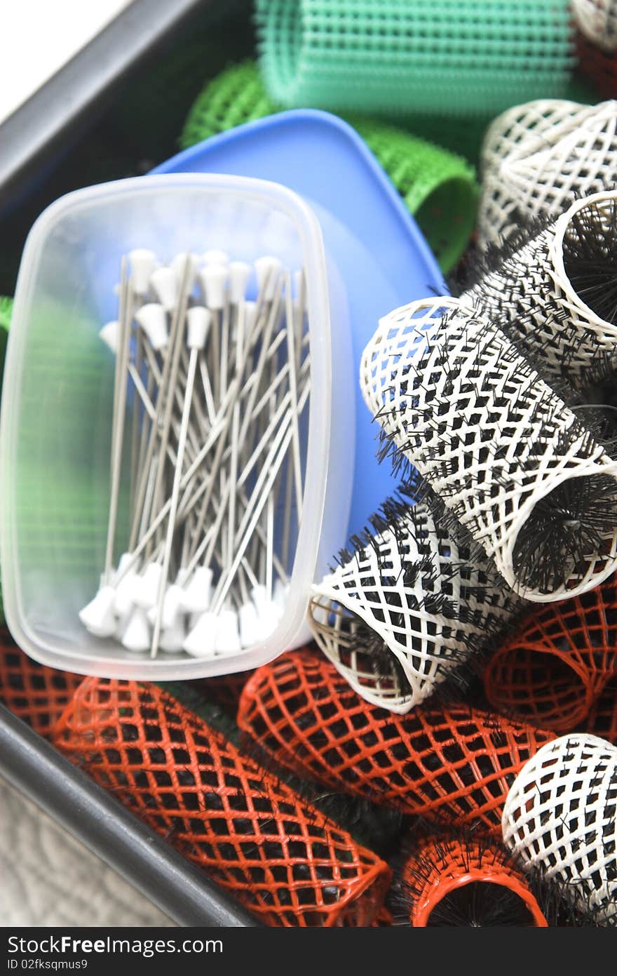 Box containing a variety of hair curlers and pins