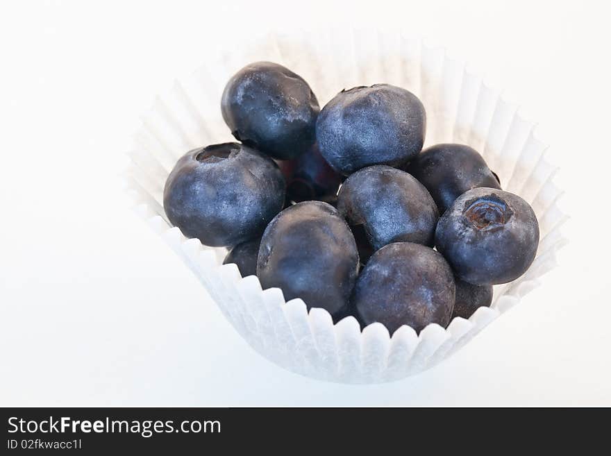 Fresh blueberries in a white paper muffin cup - isolated. Fresh blueberries in a white paper muffin cup - isolated