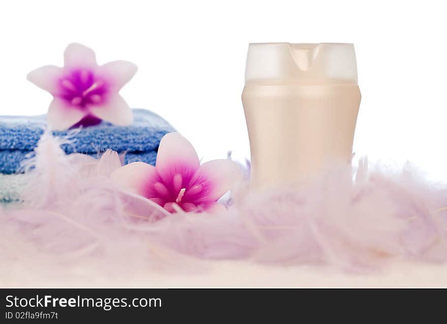 Lotion in white tube with flowers and towel decorated with feathers. Lotion in white tube with flowers and towel decorated with feathers