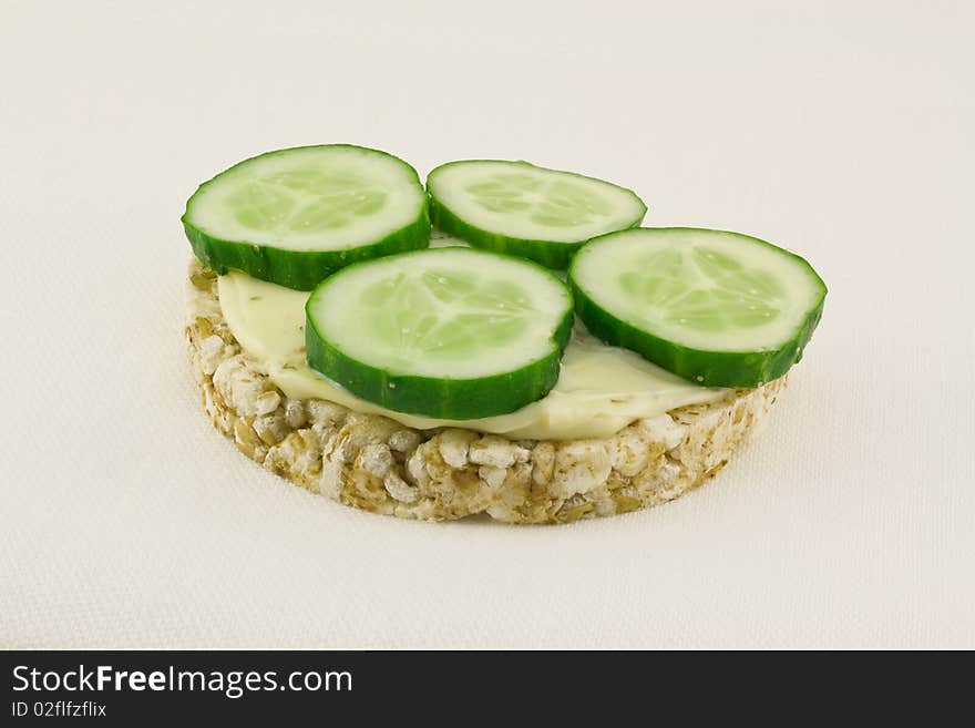 Grain small loaf with cheese and fresh cucumbers on white a linen cloth. Grain small loaf with cheese and fresh cucumbers on white a linen cloth