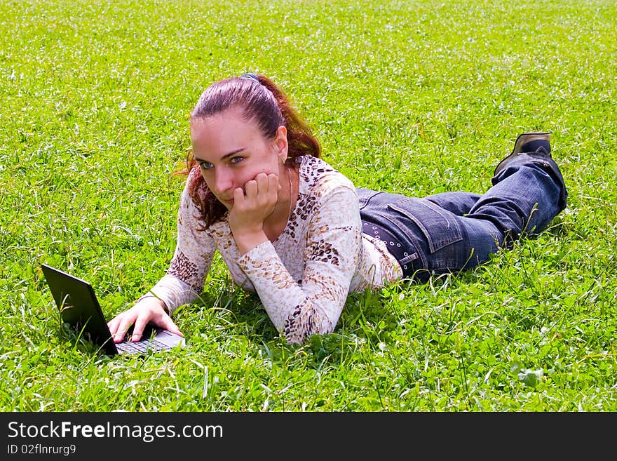 Young girl lying on green grass with laptop. Young girl lying on green grass with laptop