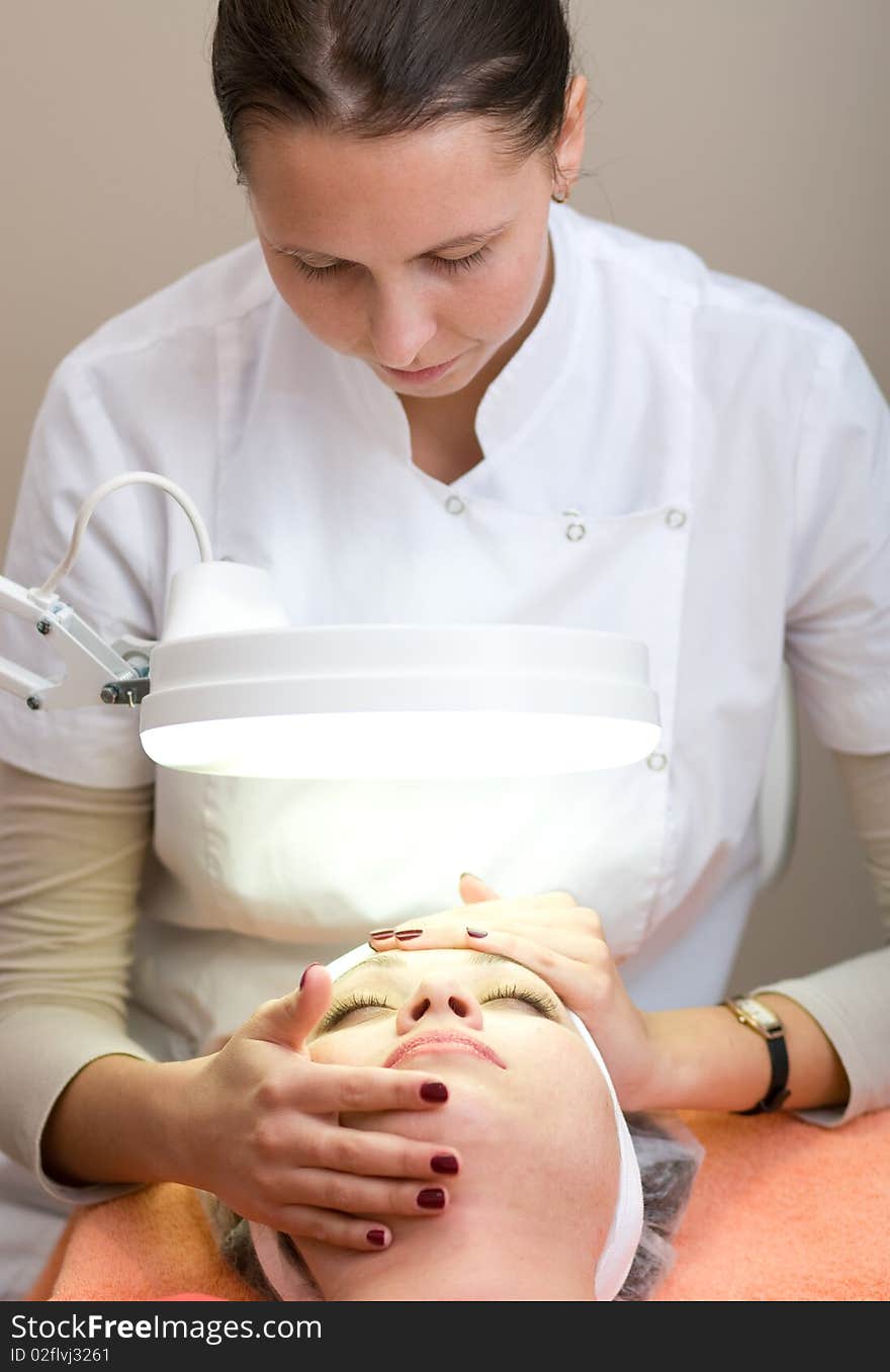 Woman in Cosmetic Cabinet under lamp. Faces skin cleaning.