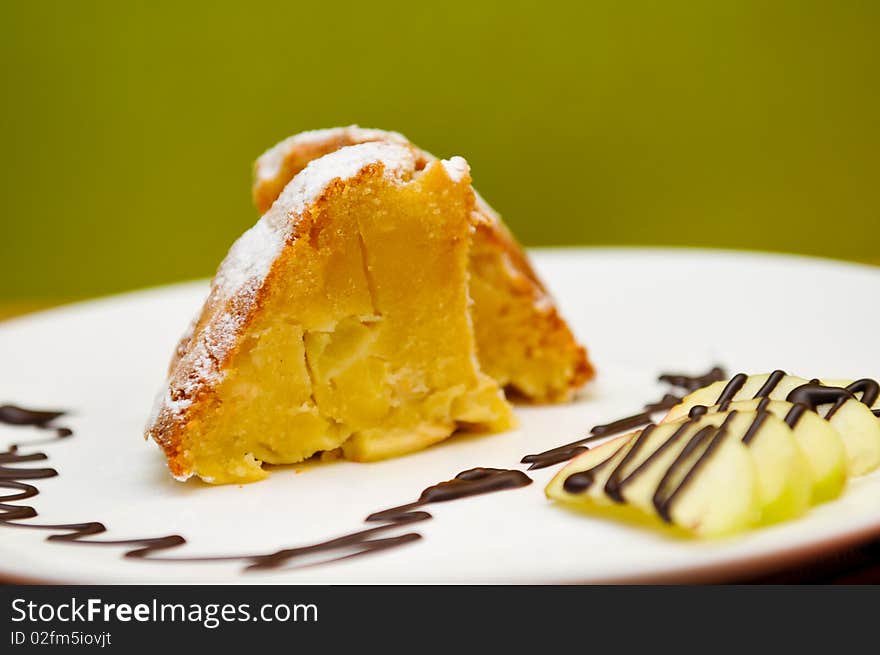 Peace of apple cake, served with apples and chocolate