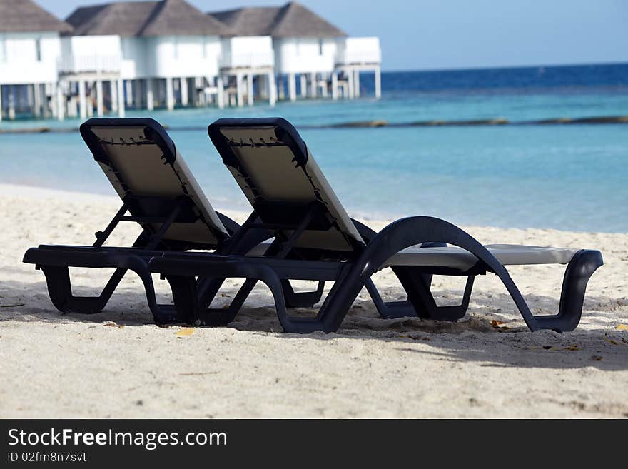 Chase lounge on beach with water villa background