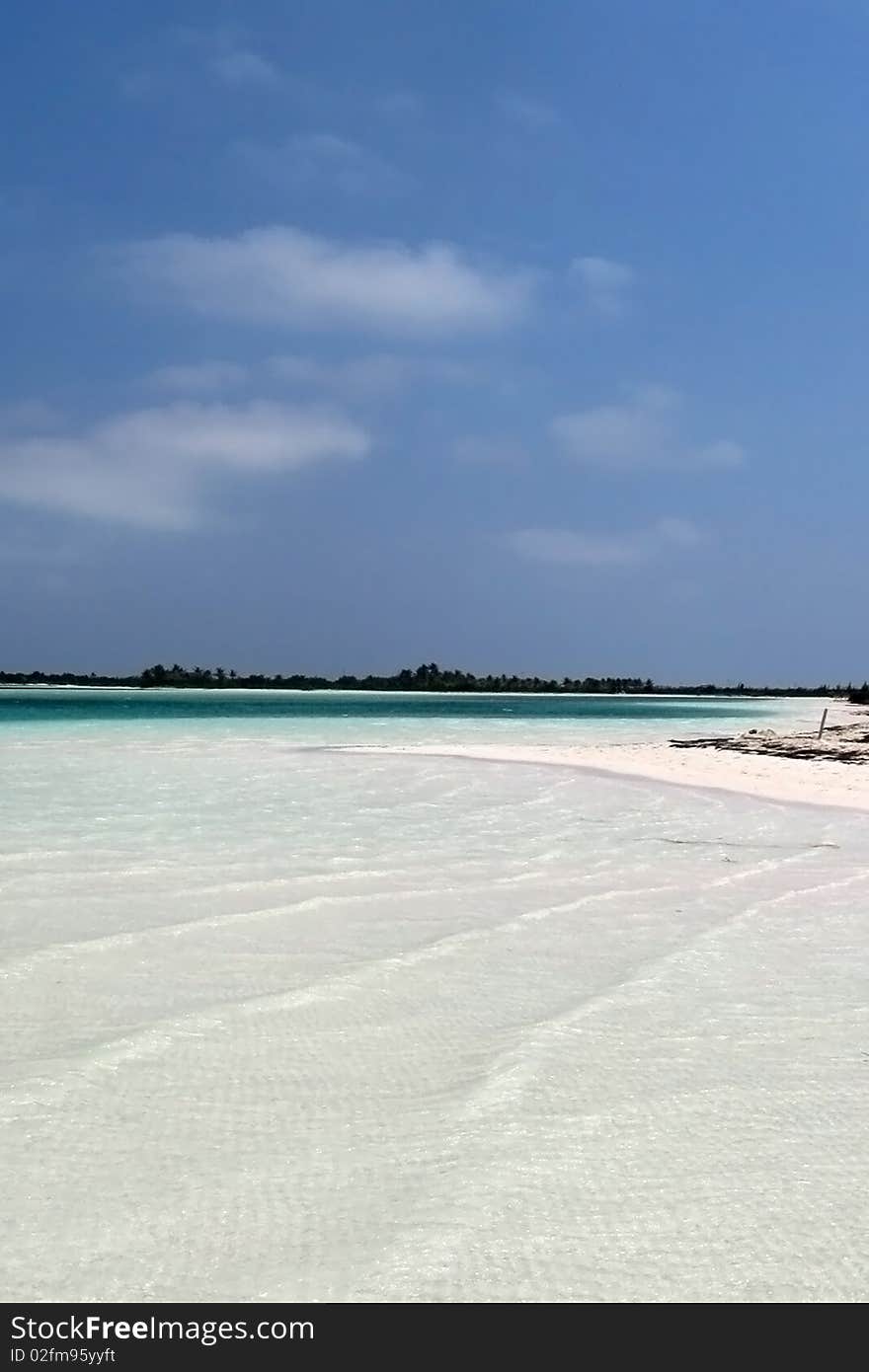 White sand beach with shallow water and turquoise blue color under blue sky and a few clouds. White sand beach with shallow water and turquoise blue color under blue sky and a few clouds