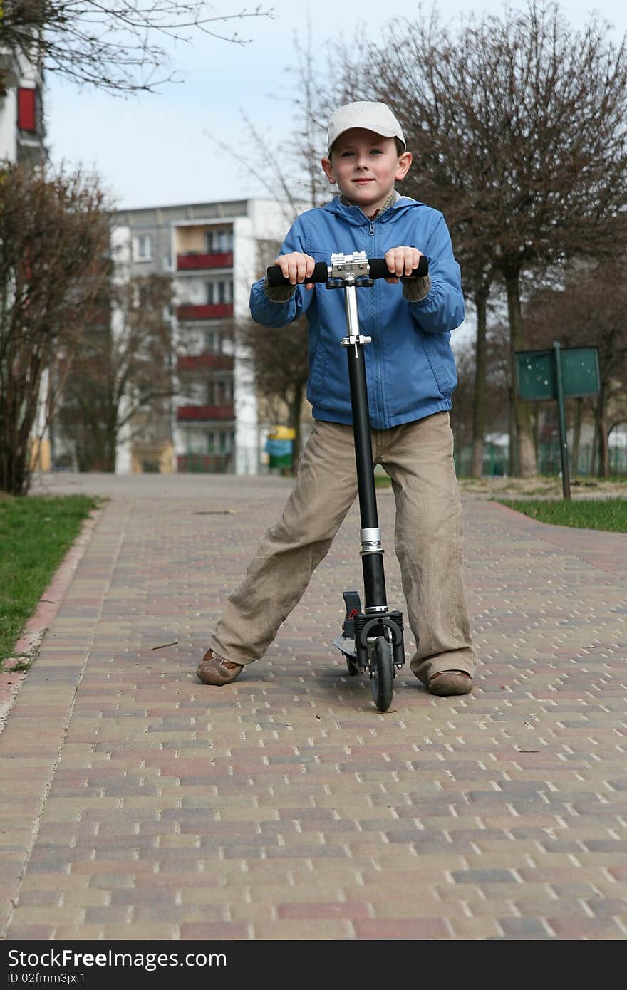 Young boy riding two wheeled scooter. Young boy riding two wheeled scooter.