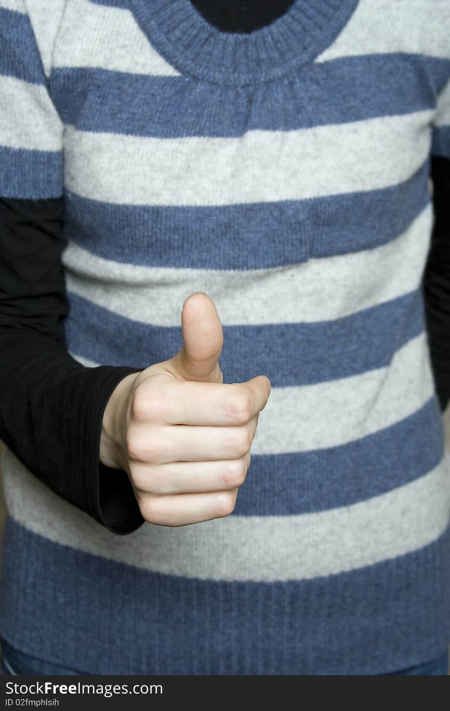 Against the background of a striped vest young white girl's hand with his thumb up. Success. Against the background of a striped vest young white girl's hand with his thumb up. Success