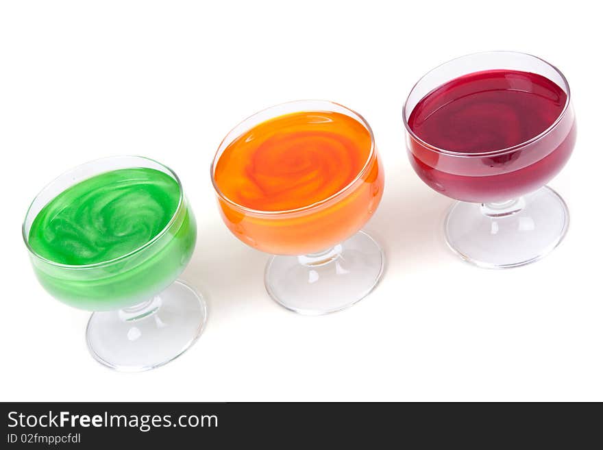 Green, yellow and red jelly in glass on white background