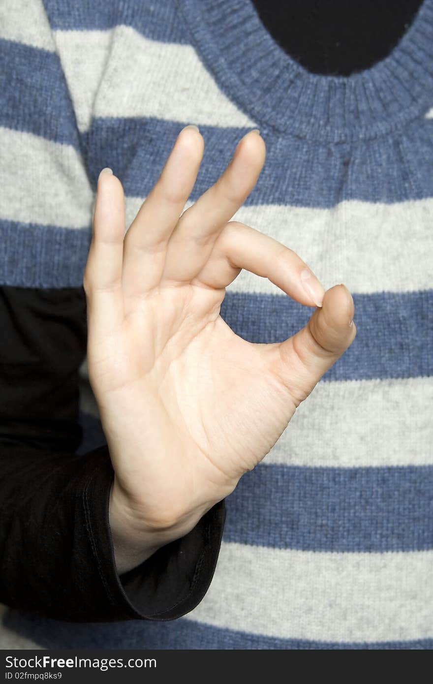 Against the background of a striped vest young white girl's hand in the ring fingers folded up. Success. Against the background of a striped vest young white girl's hand in the ring fingers folded up. Success