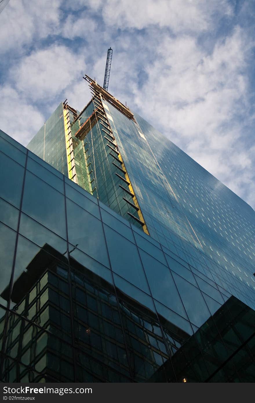 A construction crane high above a glass sckyscraper