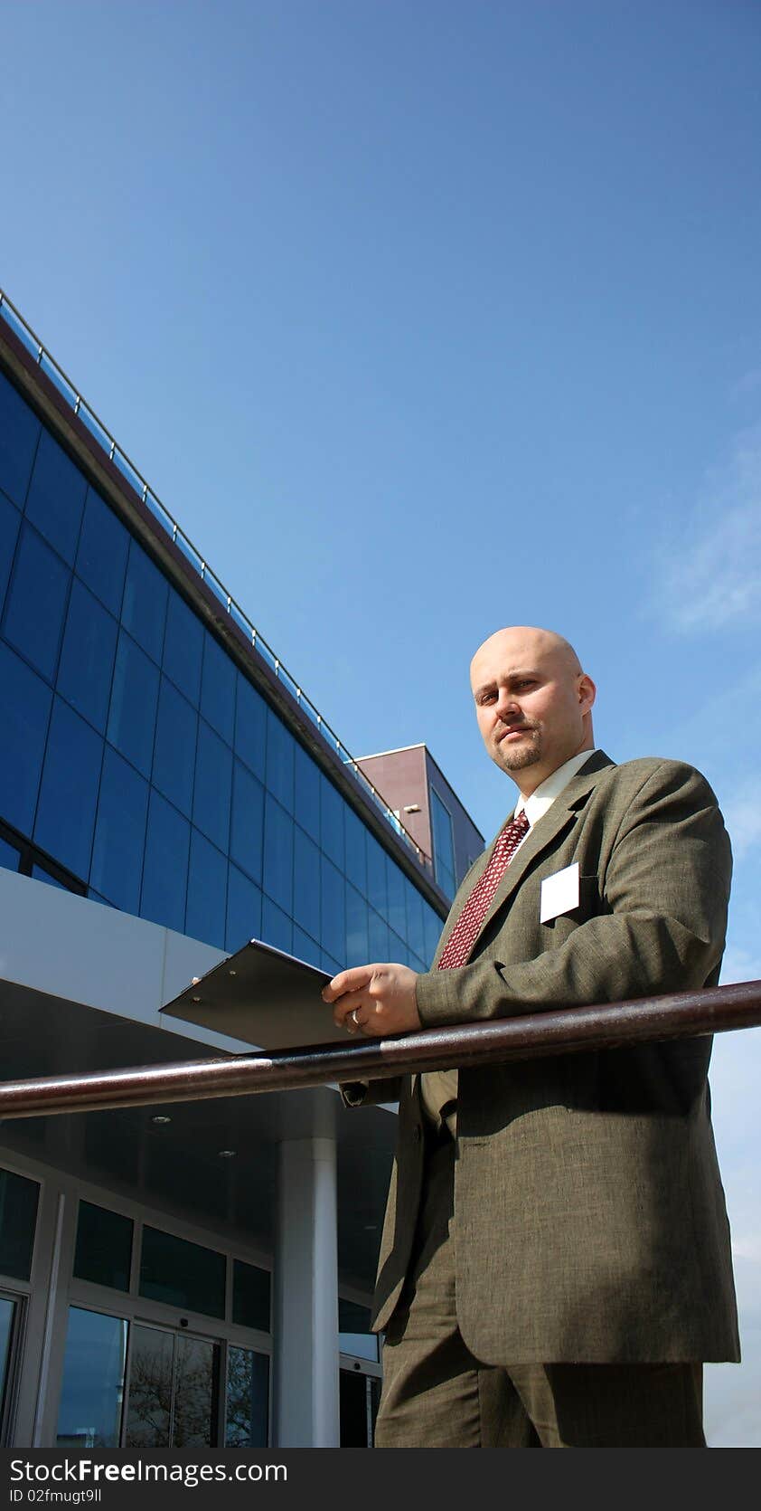 A business man in front of office building with check list. A business man in front of office building with check list