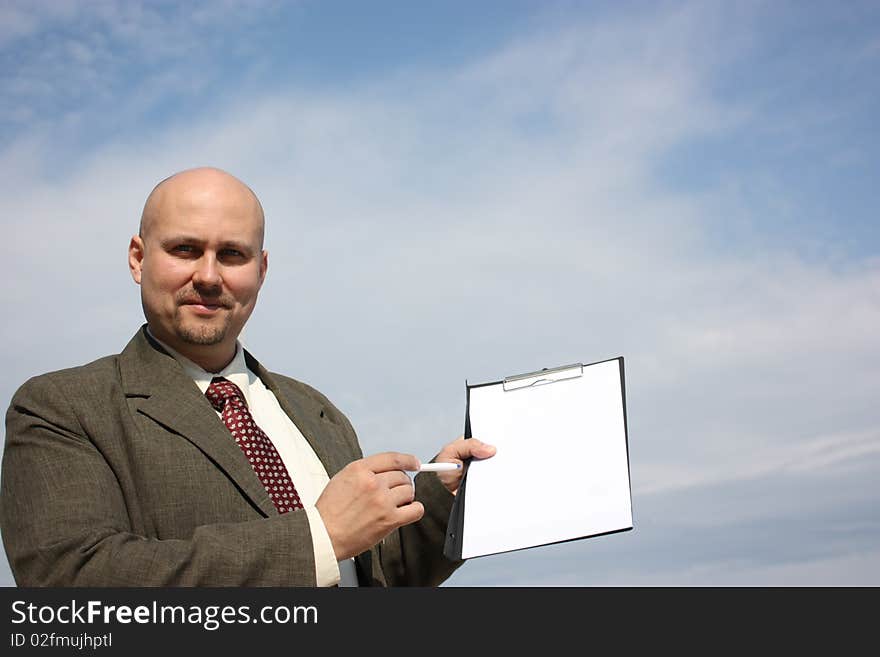 A businessman pointing a checklist on the camera isolated on a sky. A businessman pointing a checklist on the camera isolated on a sky