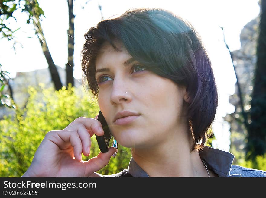 Young girl talking on the phone in the park (lens flare)