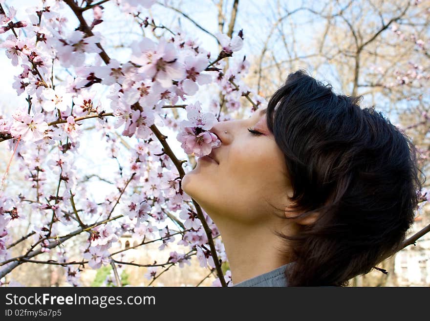 Young girl smelling the blossomming flowers of a tree. Young girl smelling the blossomming flowers of a tree