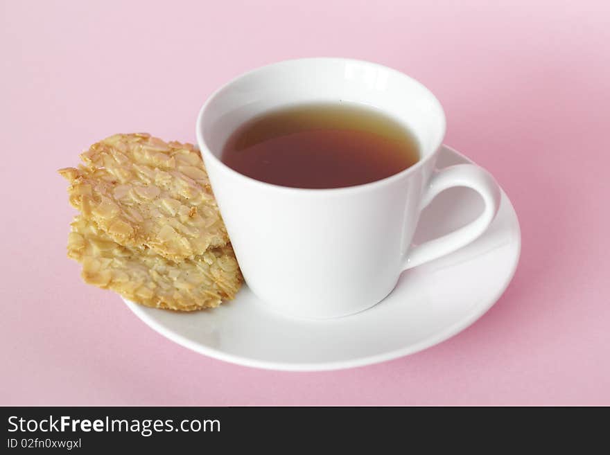 Cup of herbal tea with almond cookies on the side and a white teacup