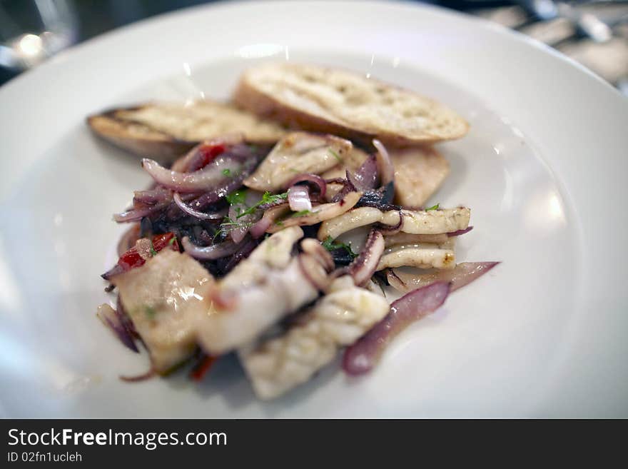 Charcoal squid with pork belly on a white plate for an appetizer