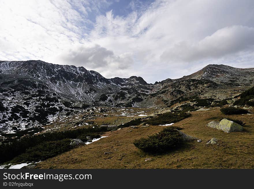 Beautiful high mountains scape with some snow and blue-cloudy sky. Beautiful high mountains scape with some snow and blue-cloudy sky