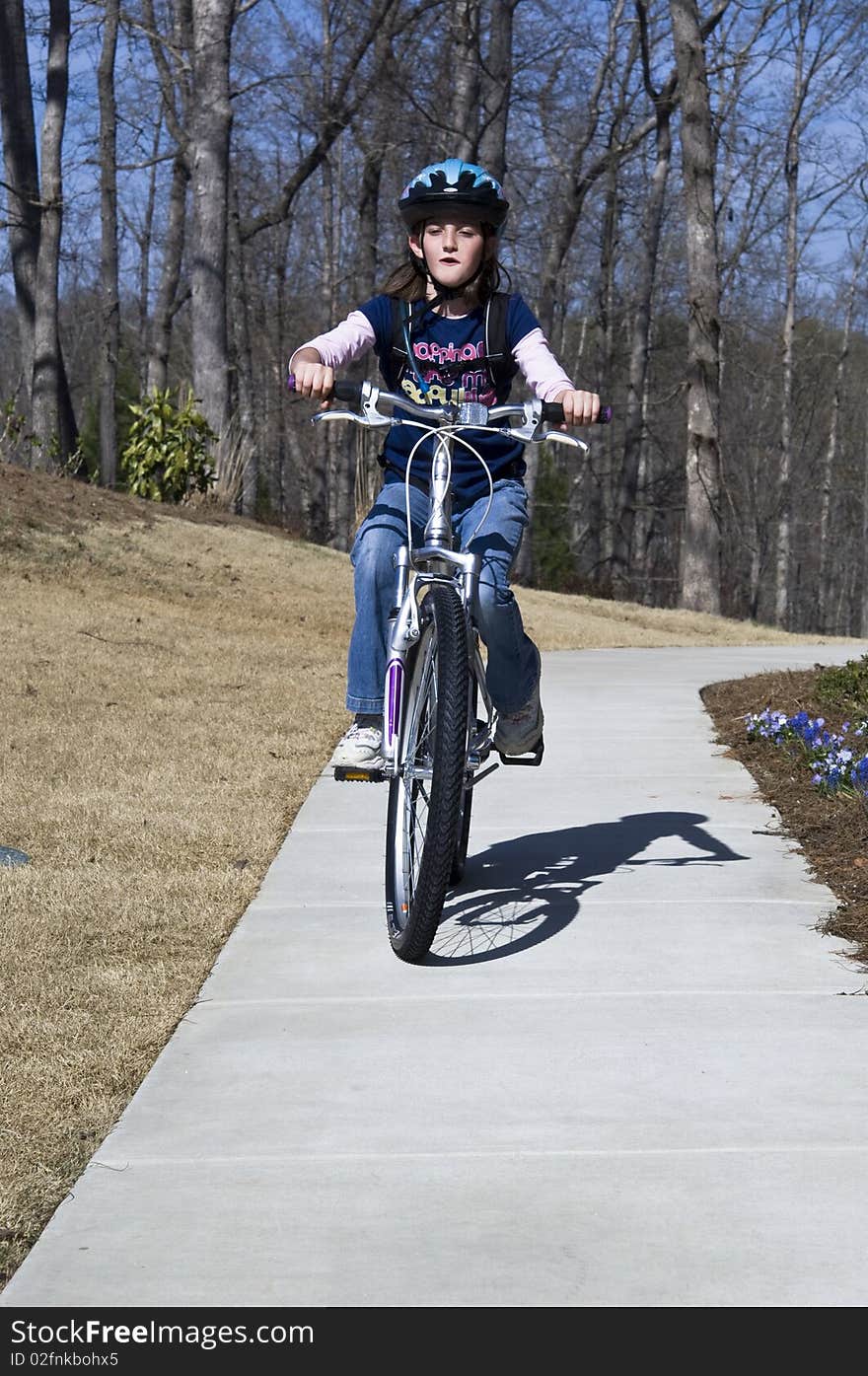 A young girl riding on a path with a cute expression of enjoyment. A young girl riding on a path with a cute expression of enjoyment.