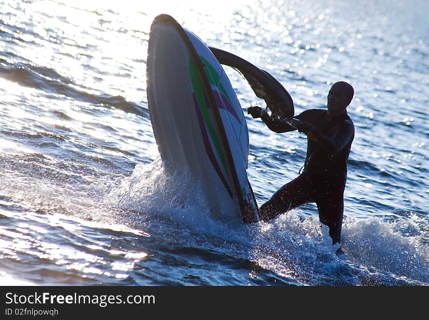 Strong man emerges on jet skis over the water at sunset . Strong man emerges on jet skis over the water at sunset .