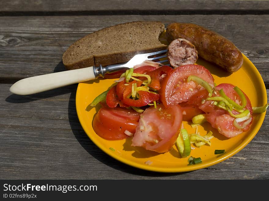 Tomato salad with sausage on the yellow plate