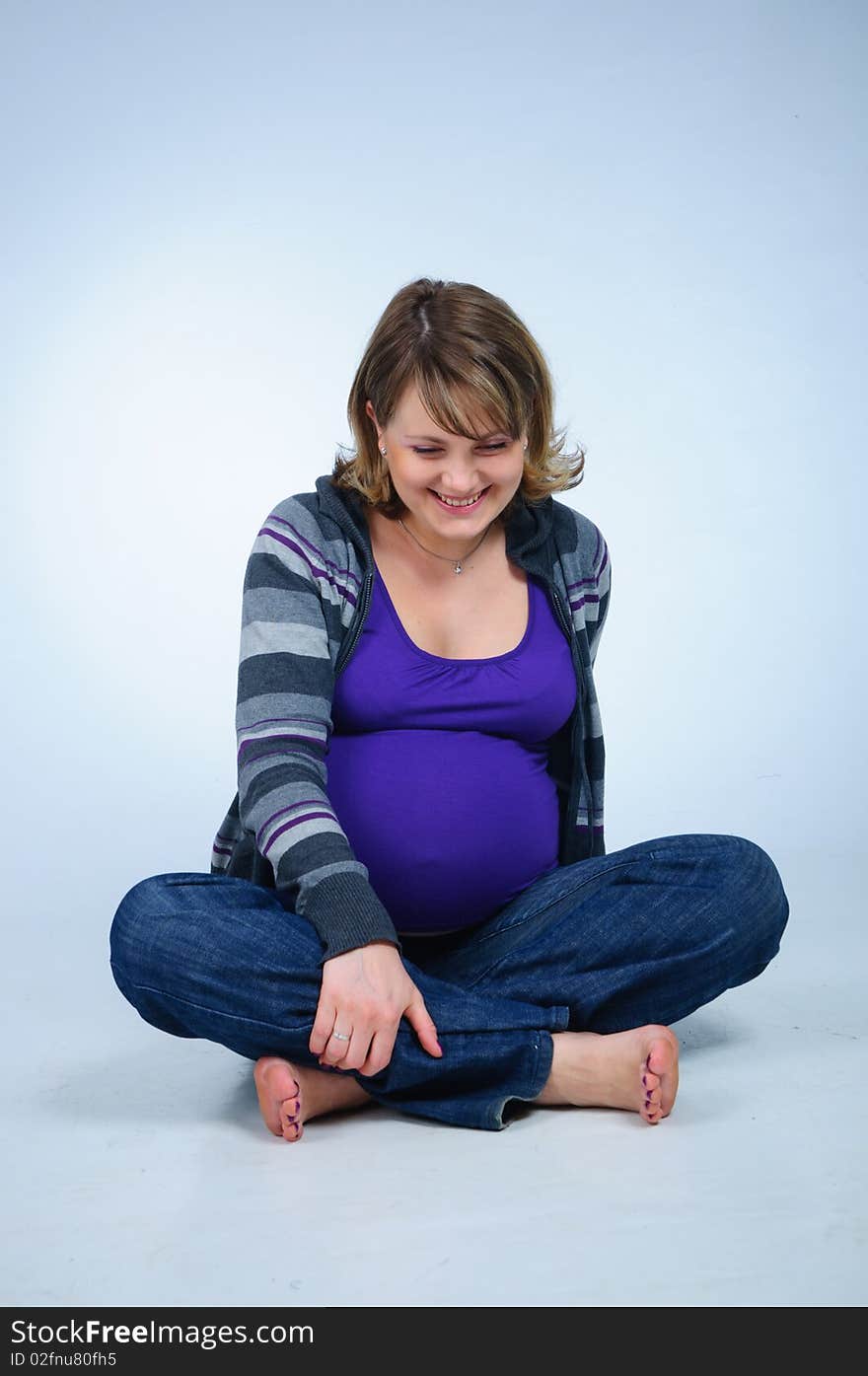 Young cute pregnant girl in a striped sweater. In studio