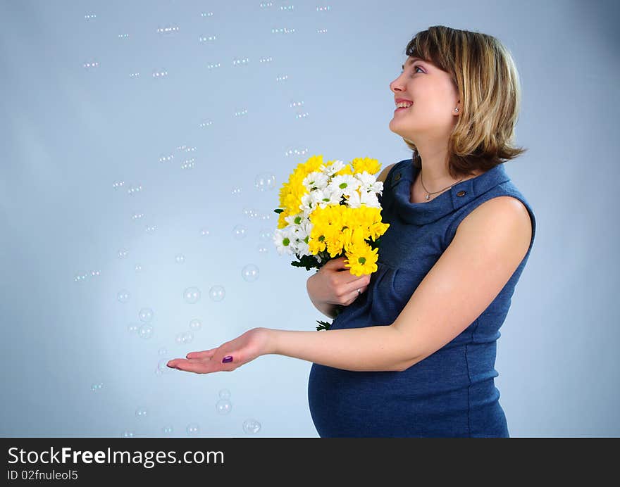 Young cute pregnant girl in a blue dress. In studio