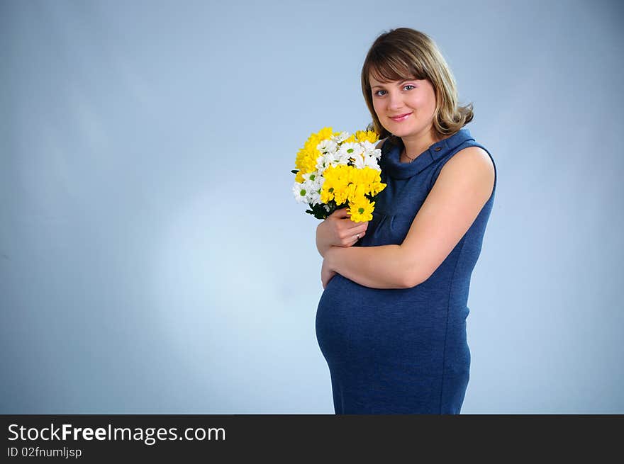 Young cute pregnant girl with bouquet of flowers