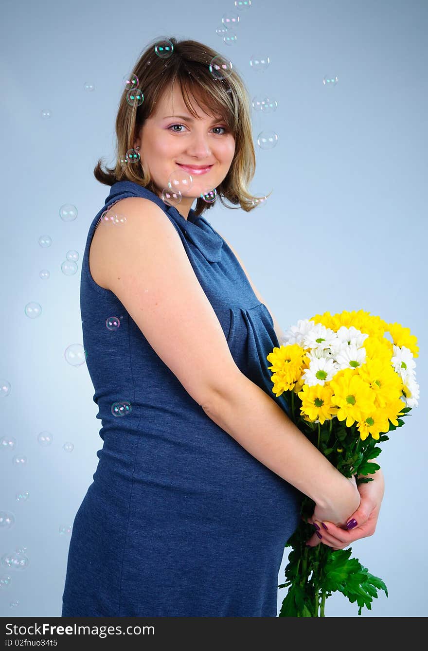 Young cute pregnant girl with bouquet of flowers