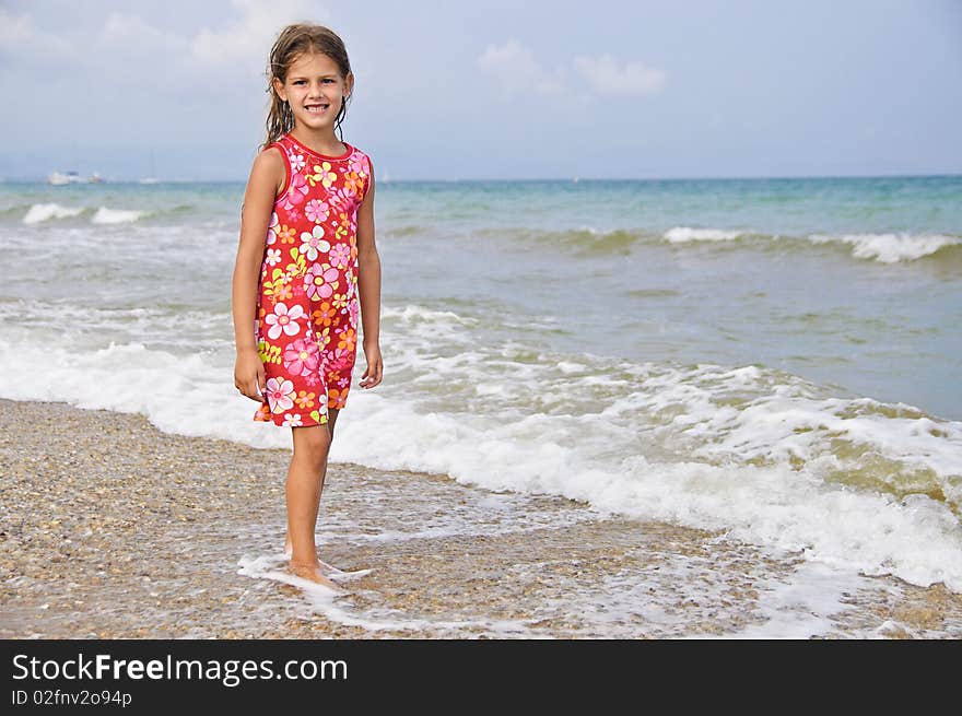 Sweet beautiful girl in a bright dress looks on the sea. Sweet beautiful girl in a bright dress looks on the sea