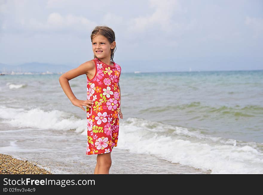 Sweet beautiful girl in a bright dress looks on the sea. Sweet beautiful girl in a bright dress looks on the sea