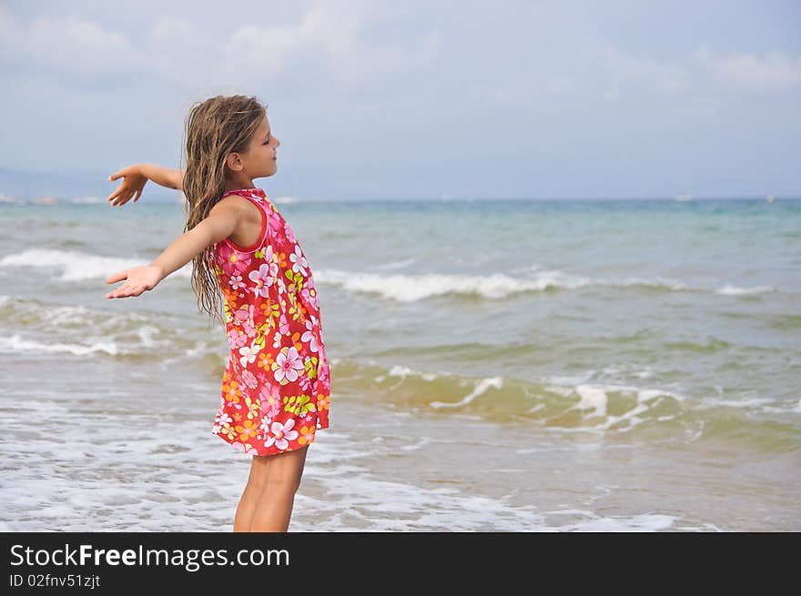 Sweet beautiful girl in a bright dress looks on the sea. Sweet beautiful girl in a bright dress looks on the sea